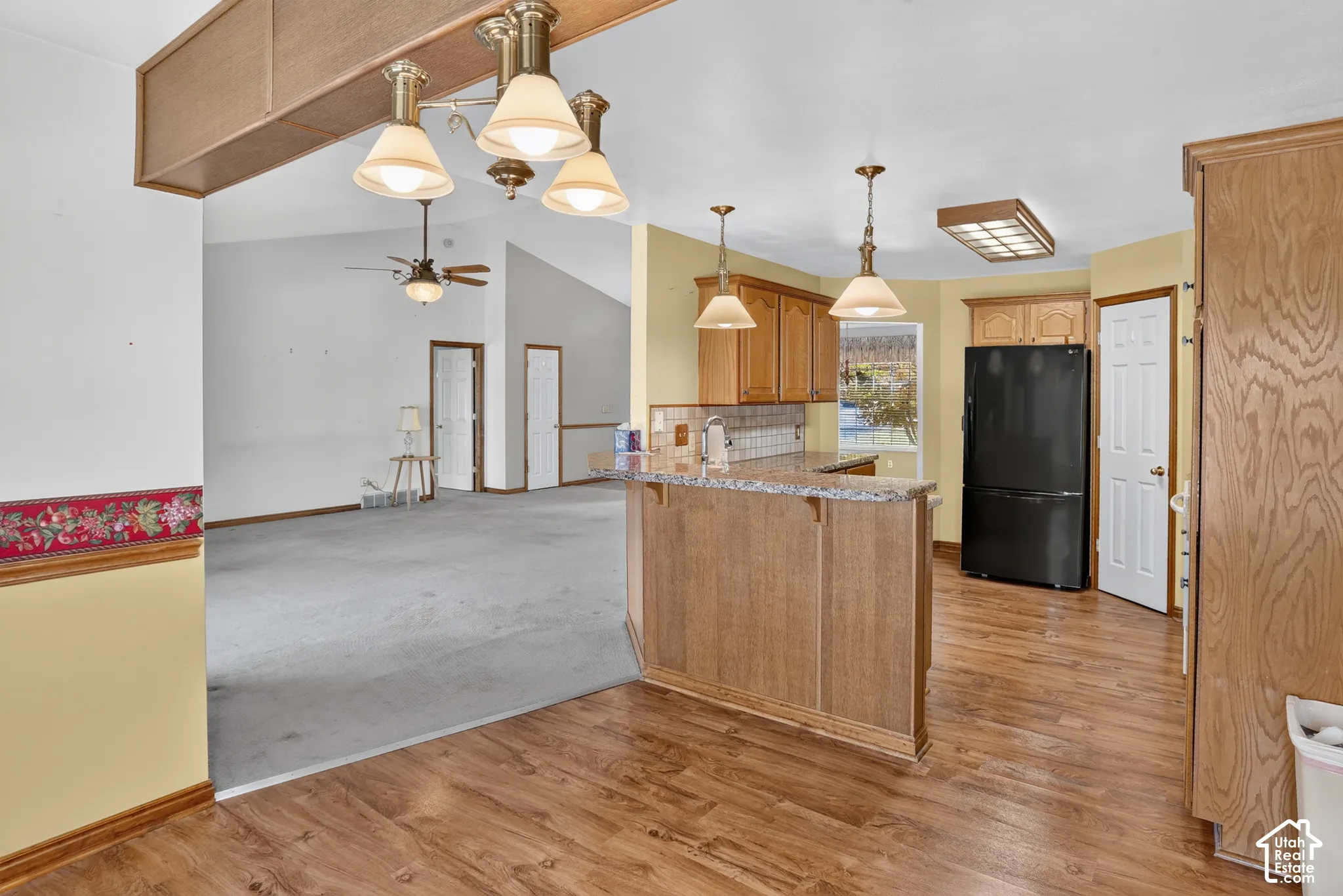 Kitchen featuring wood-finish cabinetry, stone-patterned countertops, a breakfast bar, and pendant lighting