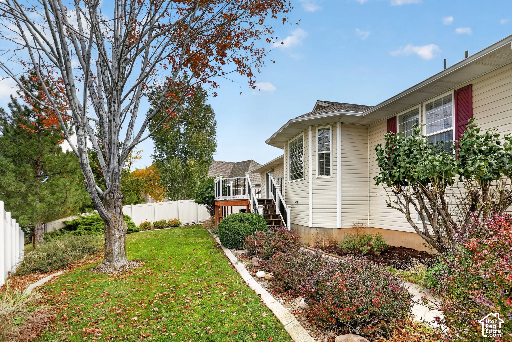 Exterior siding, vinyl fence, elevated deck with railing, and landscaped garden beds