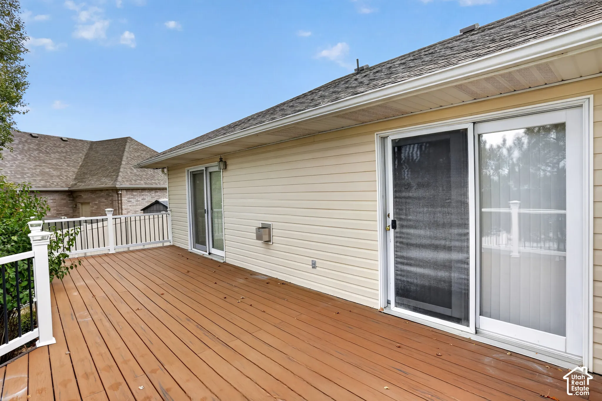 Spacious deck featuring wood-finish flooring, white railing with black metal balusters, and two sets of sliding glass doors