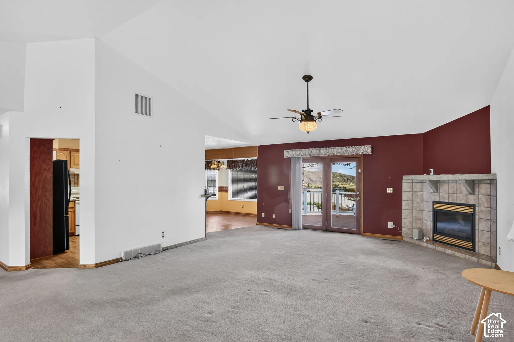 Vaulted ceilings, floor-to-ceiling tile fireplace, glass paneled sliding doors, and a multi-blade ceiling fan