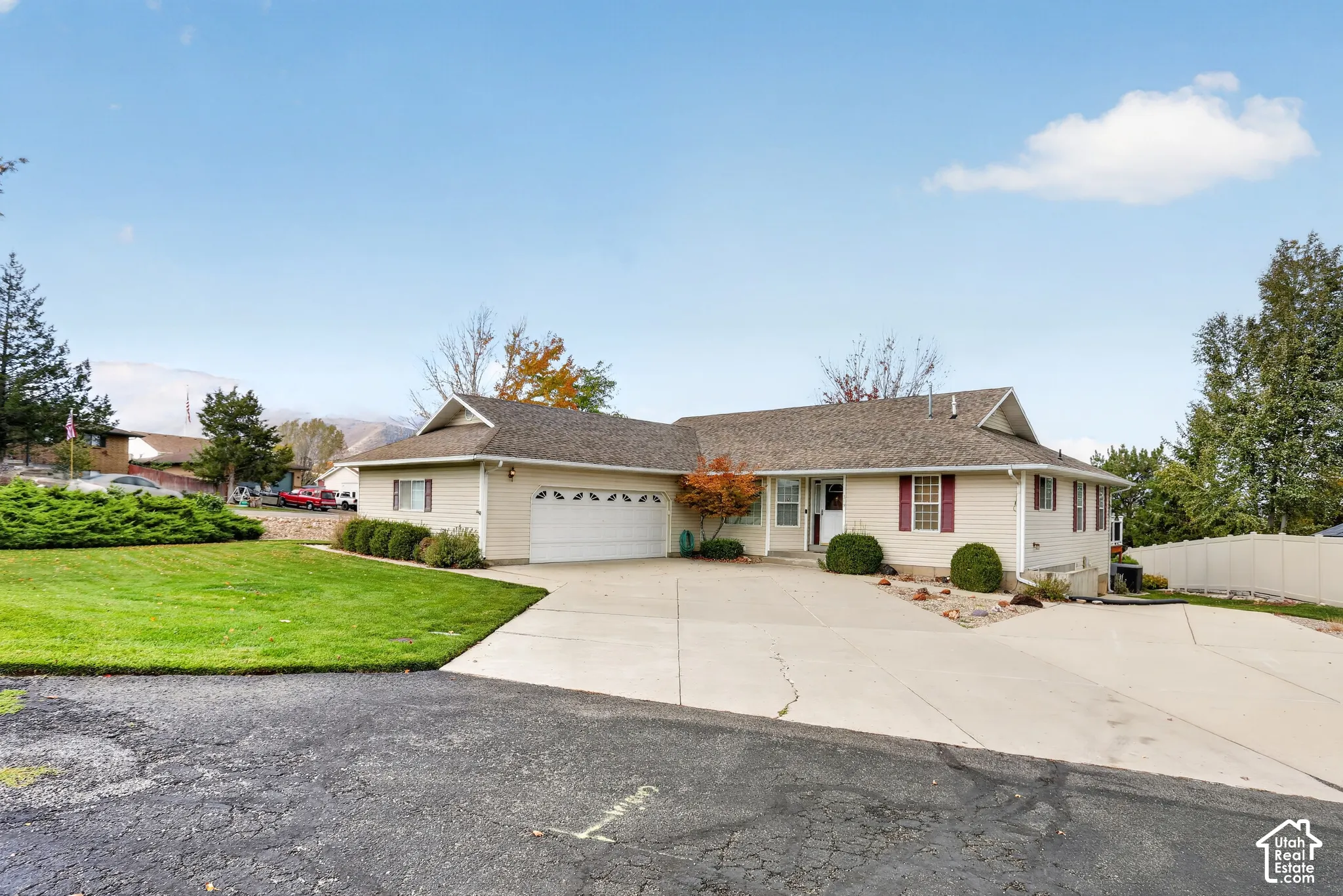 Single-story exterior featuring light-toned horizontal siding, a multi-car garage, concrete driveway, and a multi-pitched roof