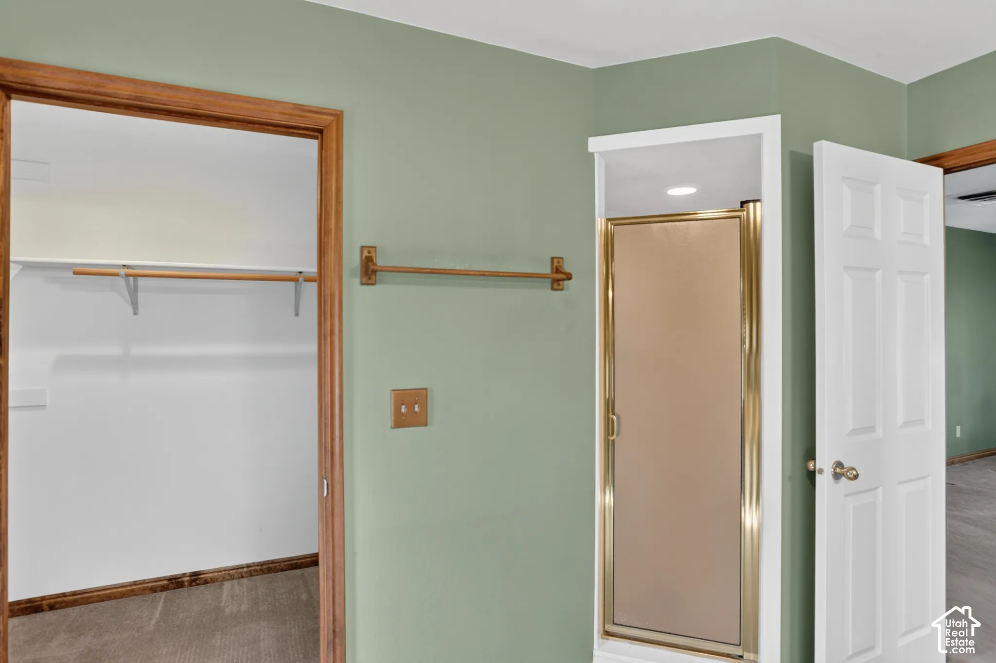 Walk-in closet featuring built-in shelving and a hanging rod, shower enclosure with a metallic frame, six-panel interior door, and hardware finishes