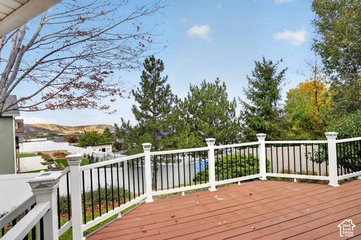 Elevated multi-level deck featuring composite decking, white vinyl railings with integrated solar cap lights, and black metal balusters