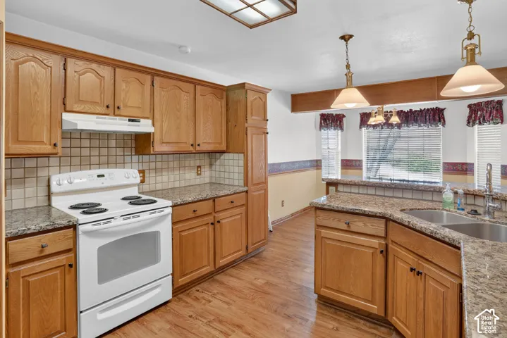 Kitchen featuring natural wood cabinetry, stone-surface countertops, square tile backsplash, wood-finish flooring, and pendant lighting