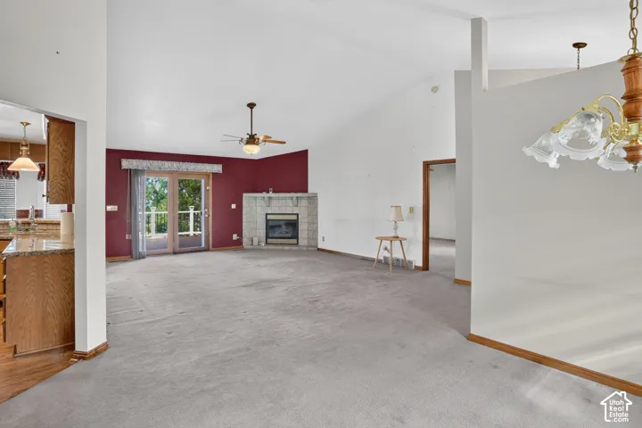 Vaulted ceilings, fireplace with tile surround, sliding glass door, ceiling fan, and chandelier