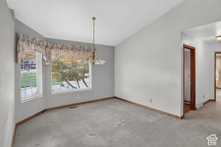 Vaulted ceiling, expansive bay window, and a decorative multi-light chandelier