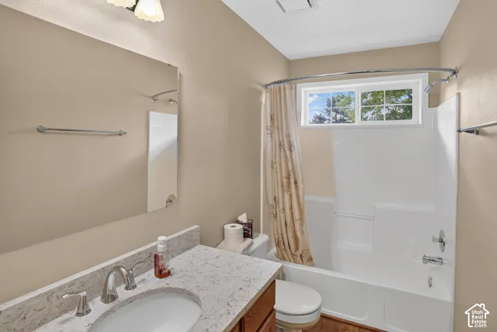Bathroom featuring a vanity with a light-toned speckled countertop, an undermount sink, a chrome faucet, a wall-mounted mirror, and a tub-shower combination with a sliding window