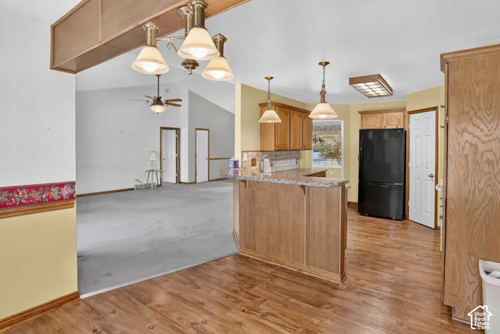 Kitchen featuring wood-finish cabinetry, stone-patterned countertops, a breakfast bar, and pendant lighting