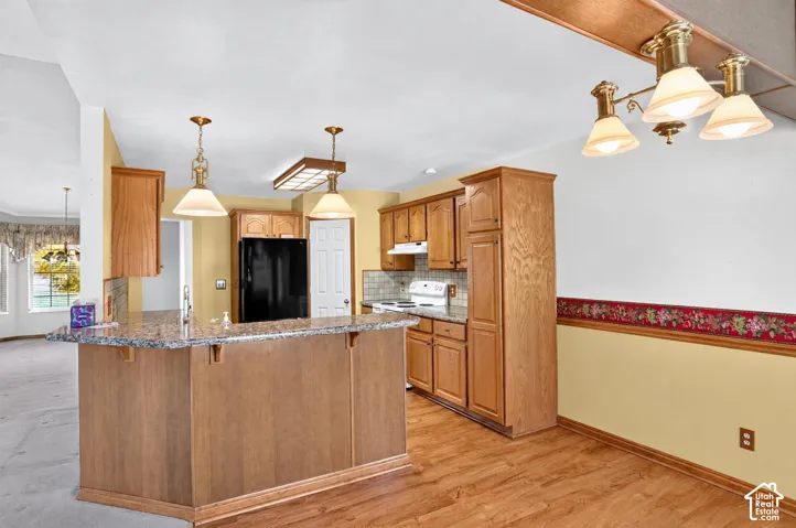 Kitchen featuring oak cabinetry, stone-finish countertops, a breakfast bar, pendant lighting, and wood-finish flooring