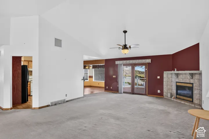 Vaulted ceilings, floor-to-ceiling tile fireplace, glass paneled sliding doors, and a multi-blade ceiling fan