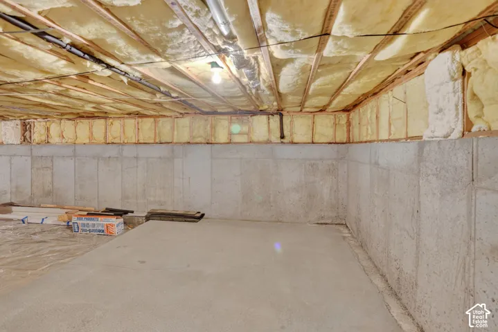 Unfinished storage area with poured concrete foundation walls, concrete floor, and exposed ceiling joists featuring spray foam insulation