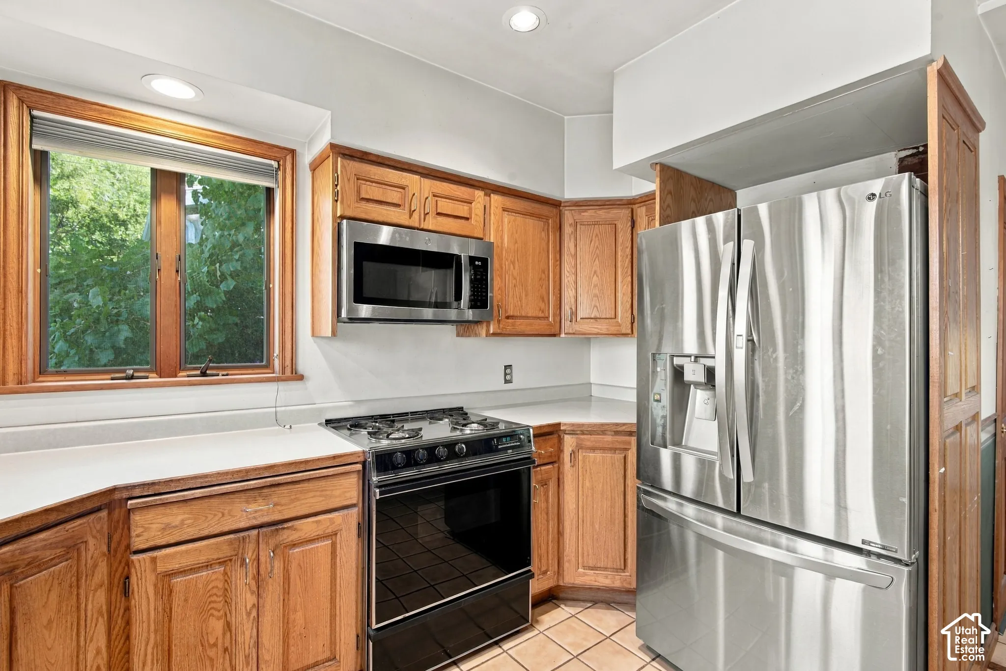 Kitchen featuring wood cabinetry, stainless steel appliances, a built-in microwave, stone-finish countertops, and recessed lighting