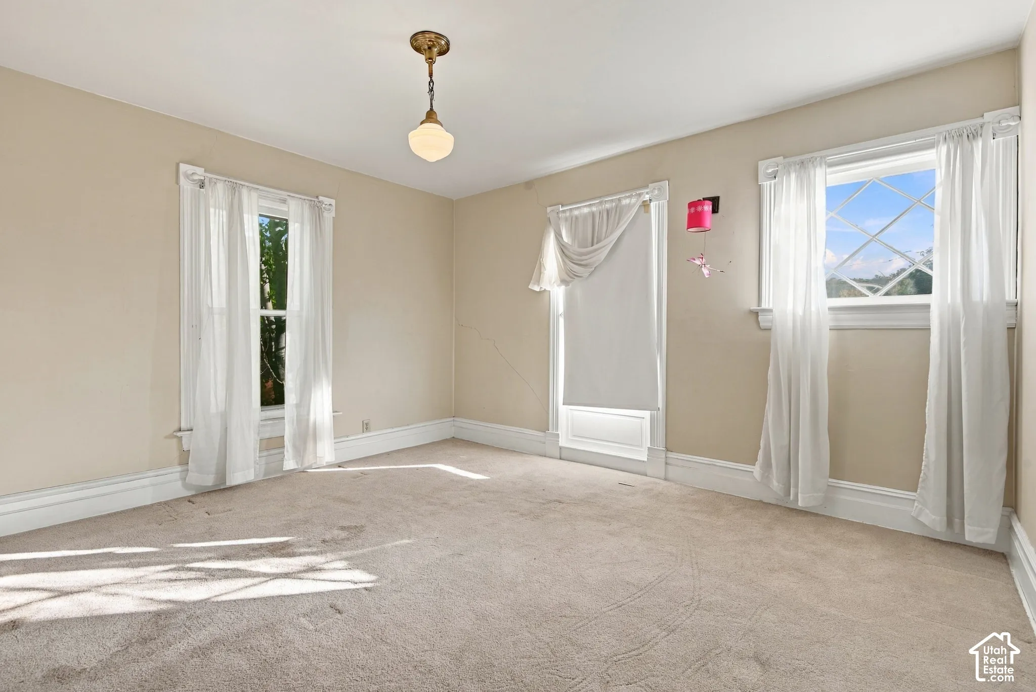 Interior room featuring neutral wall tones, multi-pane windows with casing, and a vintage-style pendant light fixture