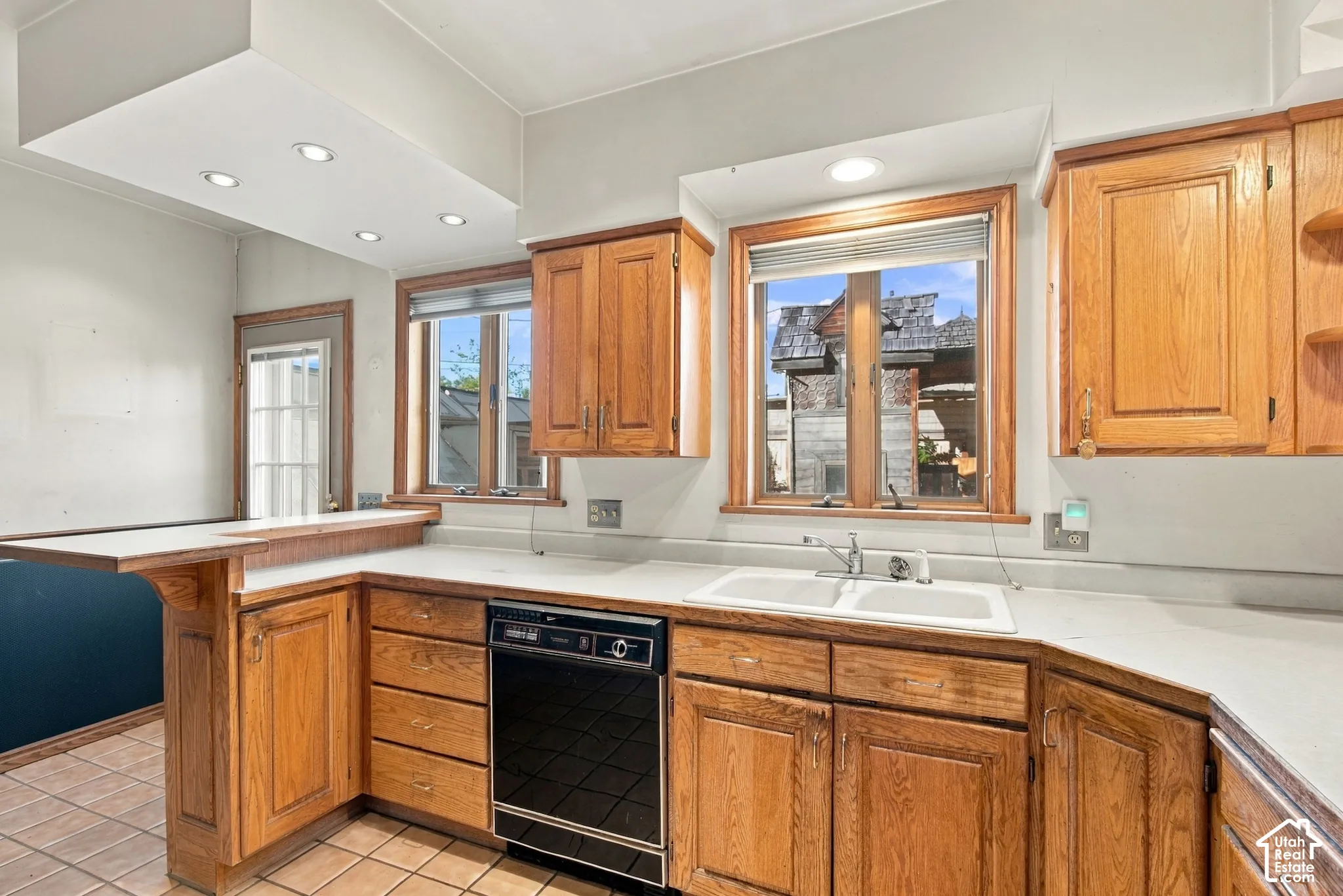 Kitchen featuring oak cabinetry, solid-surface countertops, a double-basin sink, and recessed lighting