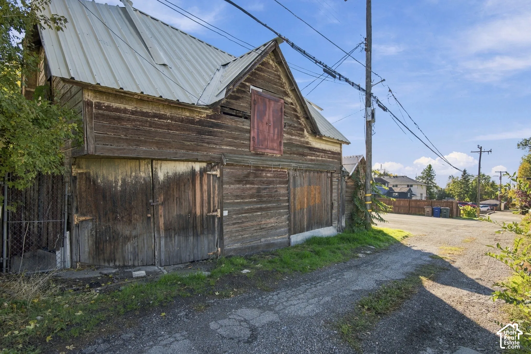 Wood-sided outbuilding featuring a metal roof, dual swing-out garage doors, and a loft access door