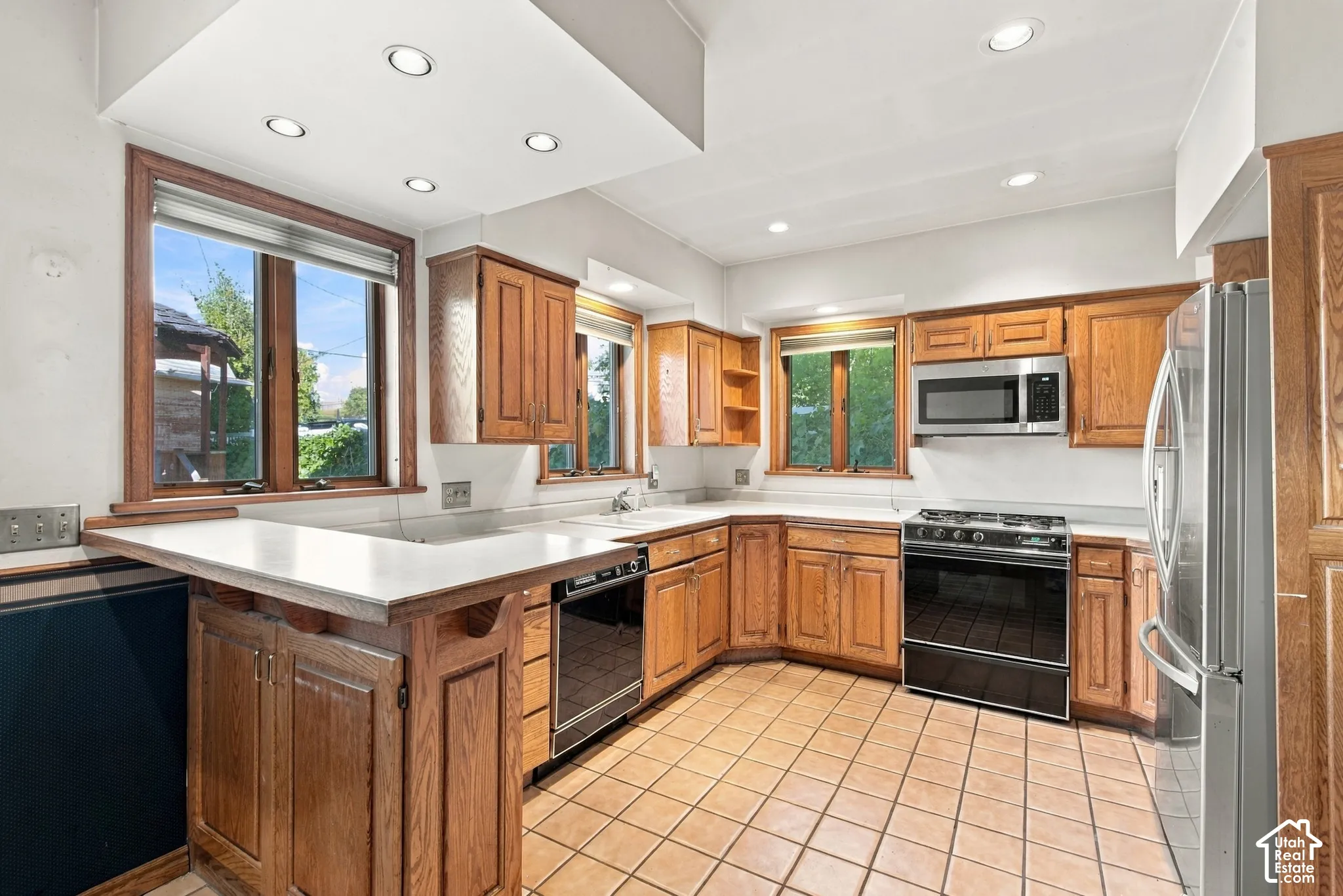 Kitchen featuring wood cabinetry, ceramic tile flooring, recessed lighting, and stainless steel appliances