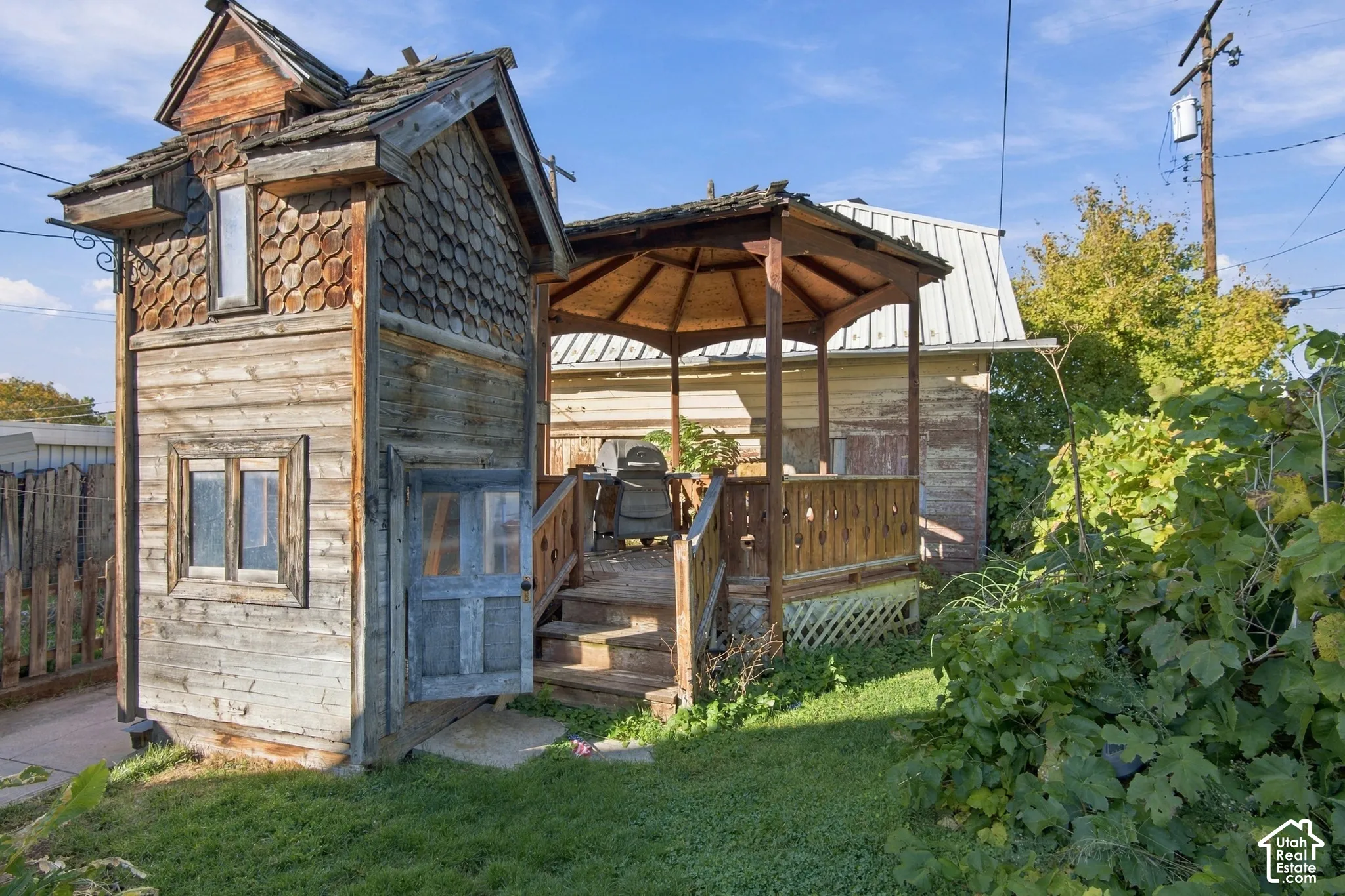 Custom wood-shingle exterior structure featuring a multi-level roofline, timber siding, a covered gazebo, and an elevated wooden deck with railing