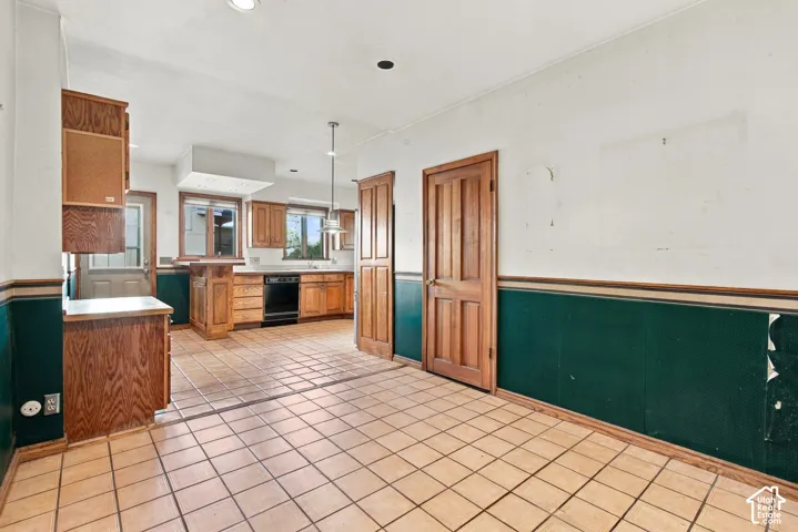 Kitchen featuring wood cabinetry, tile flooring, beadboard wainscoting, and a hanging pendant light
