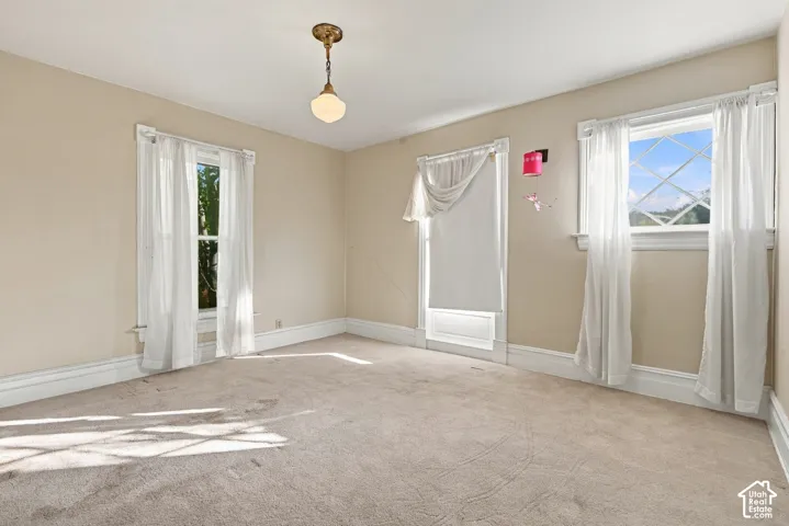 Interior room featuring neutral wall tones, multi-pane windows with casing, and a vintage-style pendant light fixture