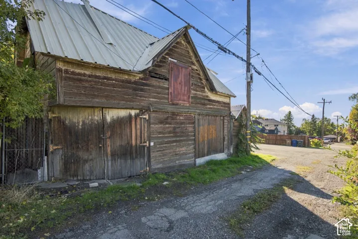 Wood-sided outbuilding featuring a metal roof, dual swing-out garage doors, and a loft access door