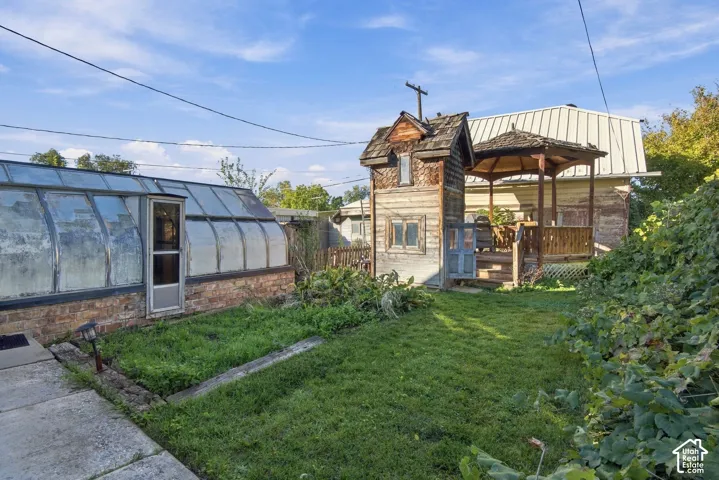 Backyard featuring a detached greenhouse with brick foundation, a multi-level wood structure with gabled roof, and an open-sided wooden gazebo