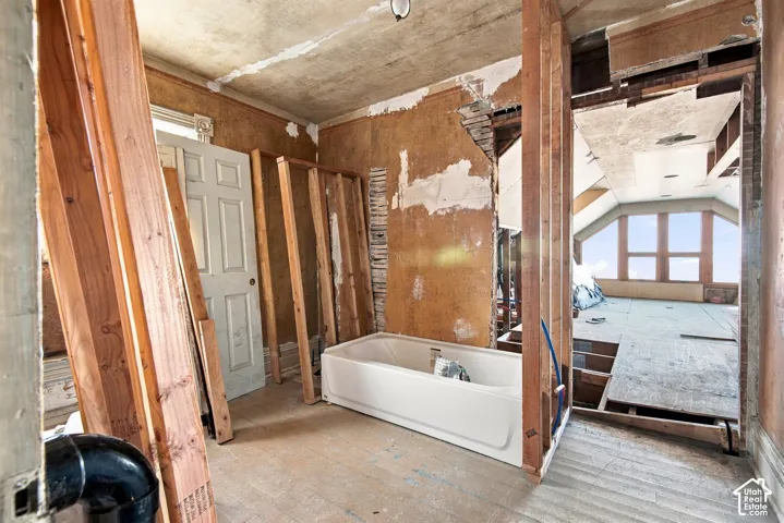 Exposed structural timber framing, acrylic bathtub, multi-pane windows, and unfinished wall surfaces