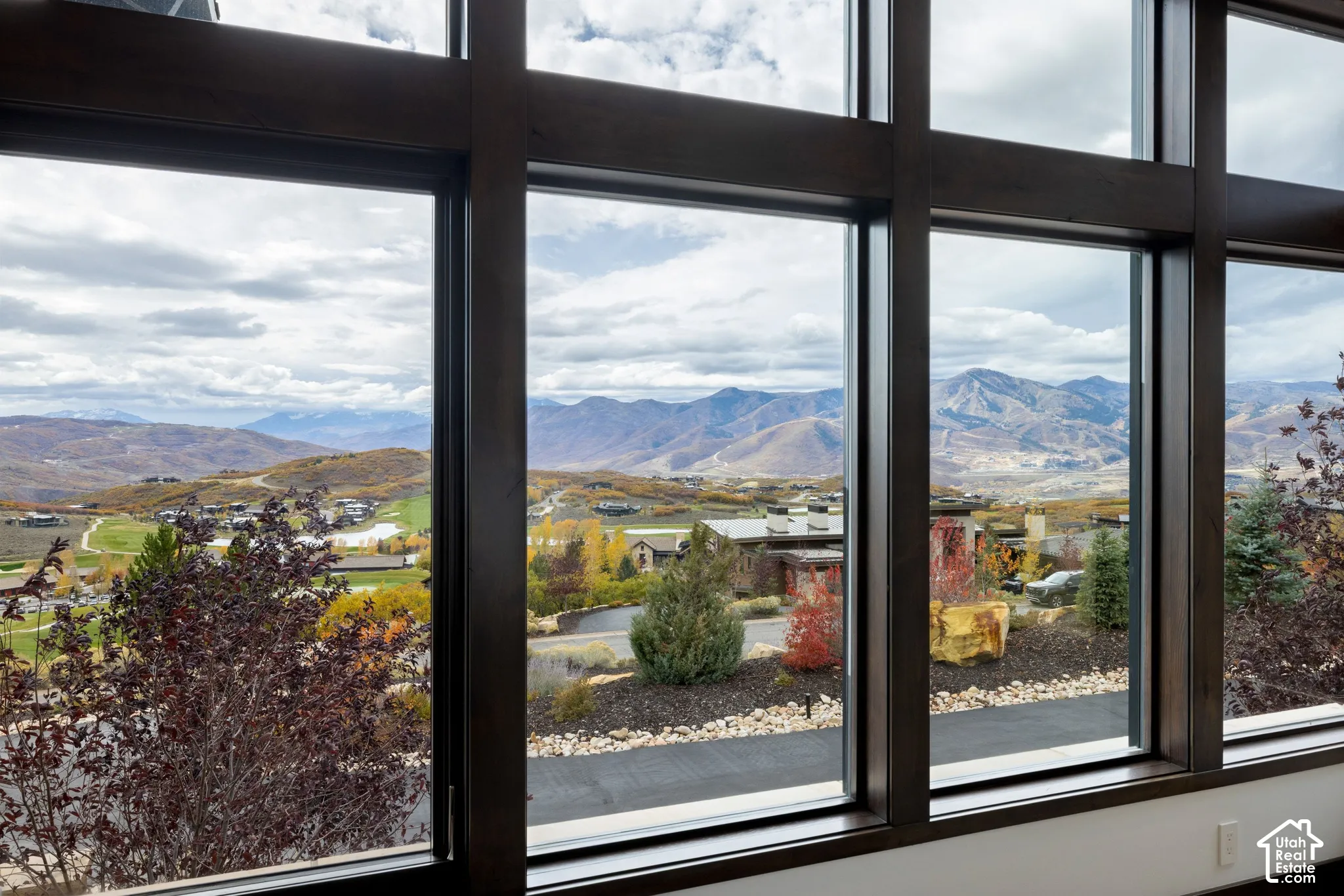Floor-to-ceiling windows with dark wood-finish framing, showcasing expansive mountain and landscape scenery