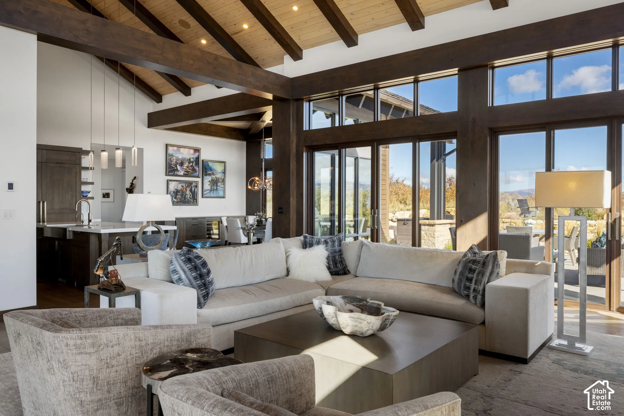 Vaulted ceiling with exposed timber beams, expansive floor-to-ceiling windows, wood-finish flooring, and recessed lighting