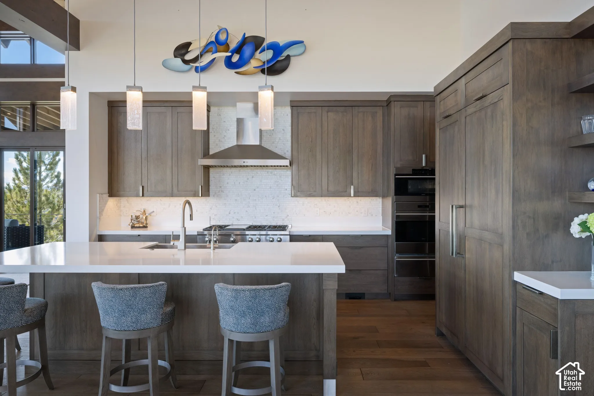 Kitchen featuring stained wood cabinetry, quartz countertops, a stone-tiled backsplash, professional-grade stainless steel appliances, and pendant lighting