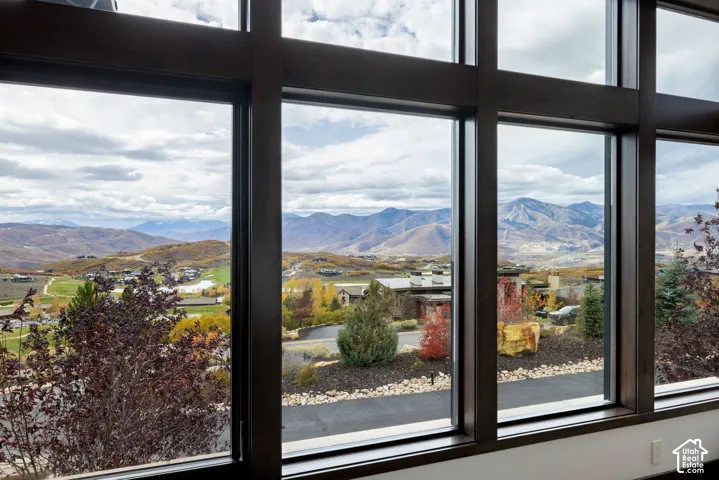 Floor-to-ceiling windows with dark wood-finish framing, showcasing expansive mountain and landscape scenery