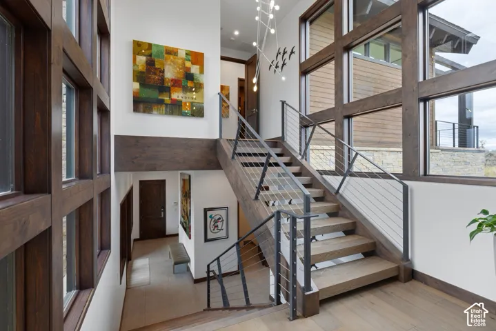 Open-riser staircase featuring thick-cut wood treads, dark metal railings, and horizontal cable balusters
