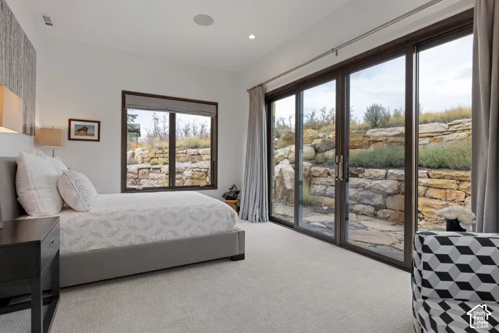 Multi-panel sliding glass doors, carpeted flooring, neutral wall finish, and a natural stone retaining wall
