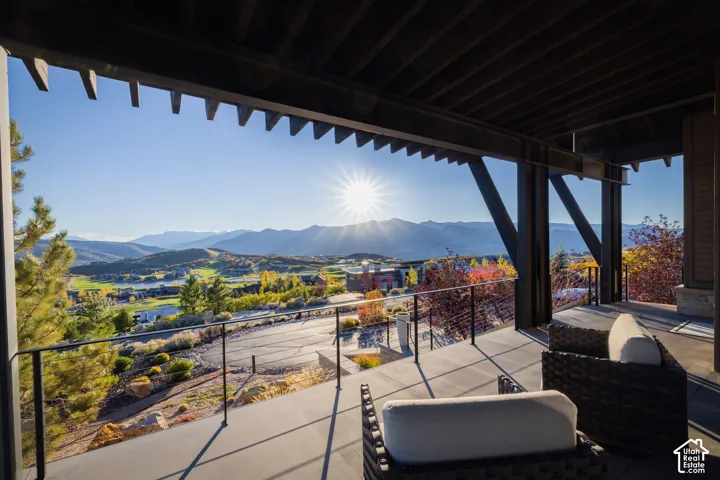 Covered terrace featuring exposed timber beams, concrete flooring, and metal cable railings, overlooking mountain and valley terrain