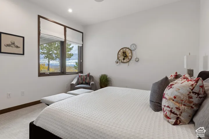 Neutral-toned carpeting, high ceilings, large window with dark frame, recessed lighting, and mountain scenery