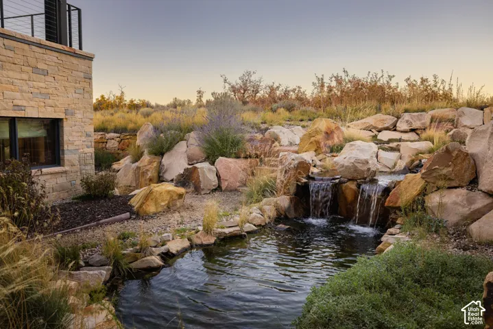 Custom stone exterior featuring a multi-tier water feature, natural boulder hardscaping, and professional xeriscaping