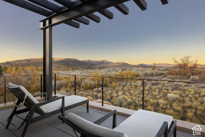 Covered terrace featuring a steel pergola, cable railing, and expansive mountain terrain backdrop