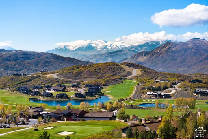 Aerial panorama featuring a golf course, multiple water features, and a backdrop of mountain ranges