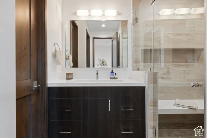Dark wood-finish vanity with a white solid surface countertop, rectangular under-mount sink, chrome faucet, frameless glass shower enclosure, and built-in shower bench