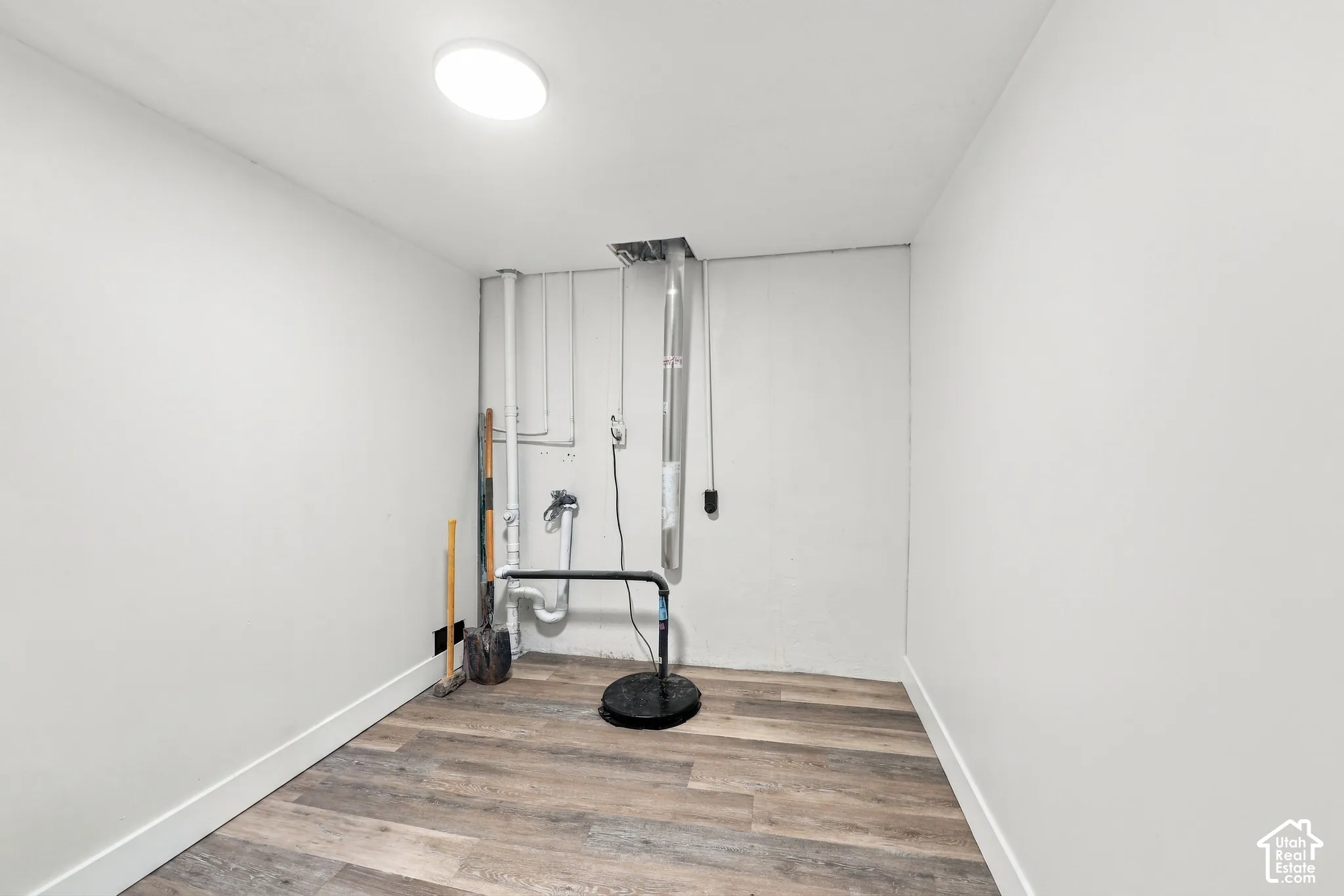 Wood-finish flooring, neutral wall paint, and overhead flush-mount lighting