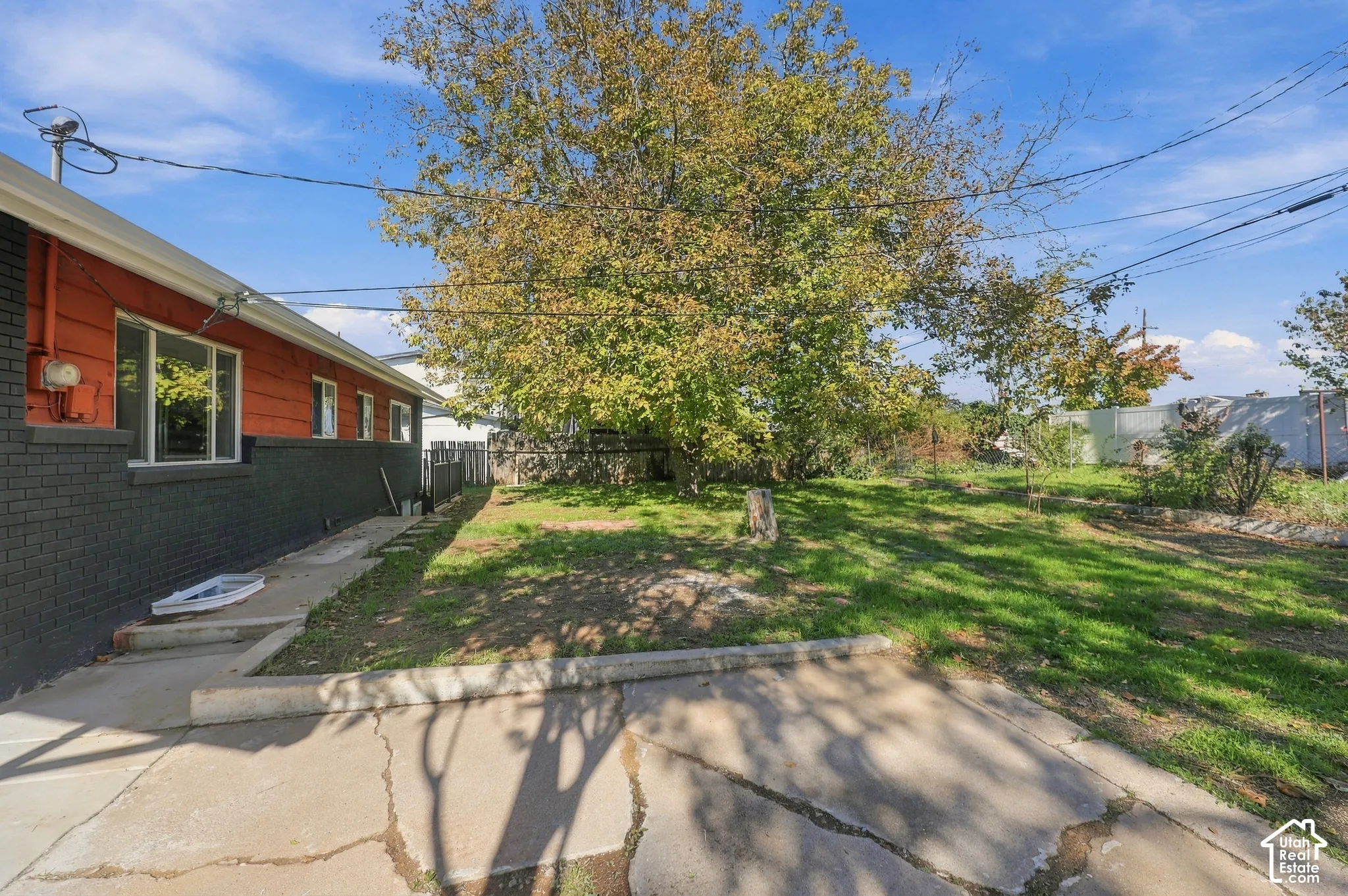 Exterior featuring a brick and horizontal siding facade, concrete patio area, and mature trees situated on a spacious lot
