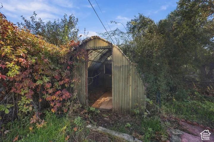 Quonset-style outdoor structure featuring a corrugated metal exterior, arched frame, and open doorway