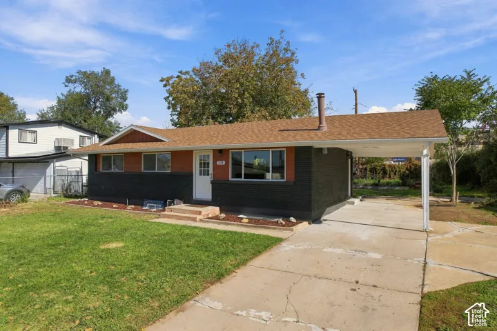 Single-story residence featuring a painted brick exterior, horizontal wood-panel siding, an asphalt shingle roof, and an attached carport