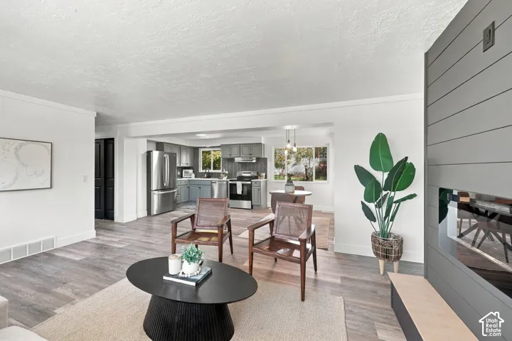 Living area featuring wood-finish flooring, a horizontal paneled accent wall, and a built-in fireplace