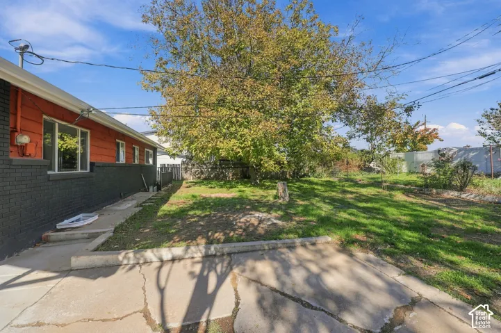 Exterior featuring a brick and horizontal siding facade, concrete patio area, and mature trees situated on a spacious lot