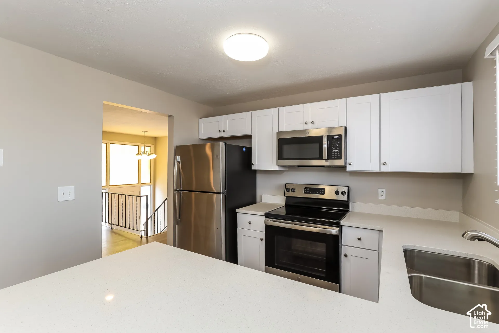 Kitchen featuring white cabinetry, solid-surface countertops, stainless steel appliances, and a dual-basin stainless steel sink