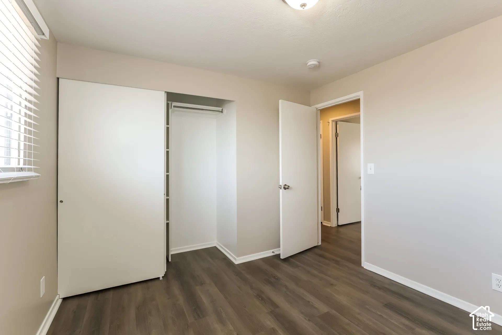 Neutral wall tones, wood-finish flooring, sliding closet doors, and horizontal blinds