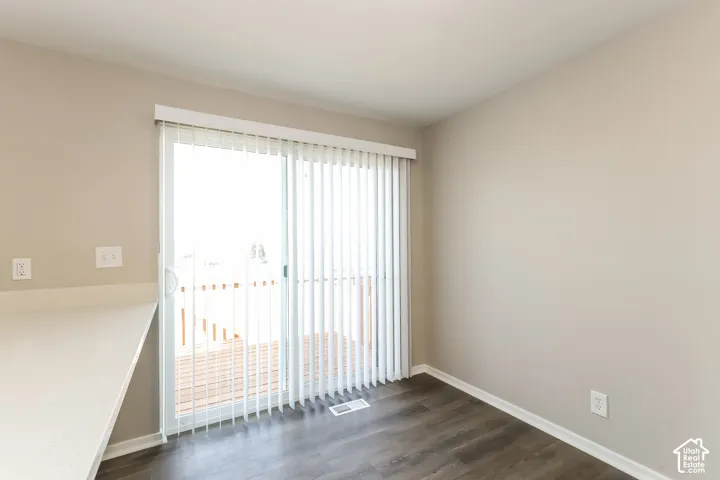 Sliding glass door with vertical blinds, wood-finish flooring, and a stone-surface counter