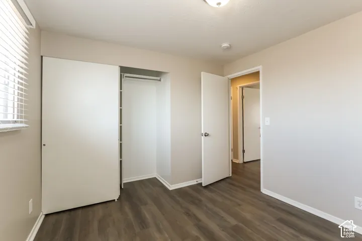 Neutral wall tones, wood-finish flooring, sliding closet doors, and horizontal blinds