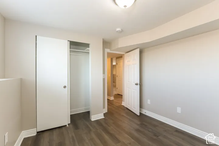 Neutral-toned interior featuring wood-finish flooring, a six-panel interior door, a reach-in closet with sliding door, and a flush-mount ceiling light fixture