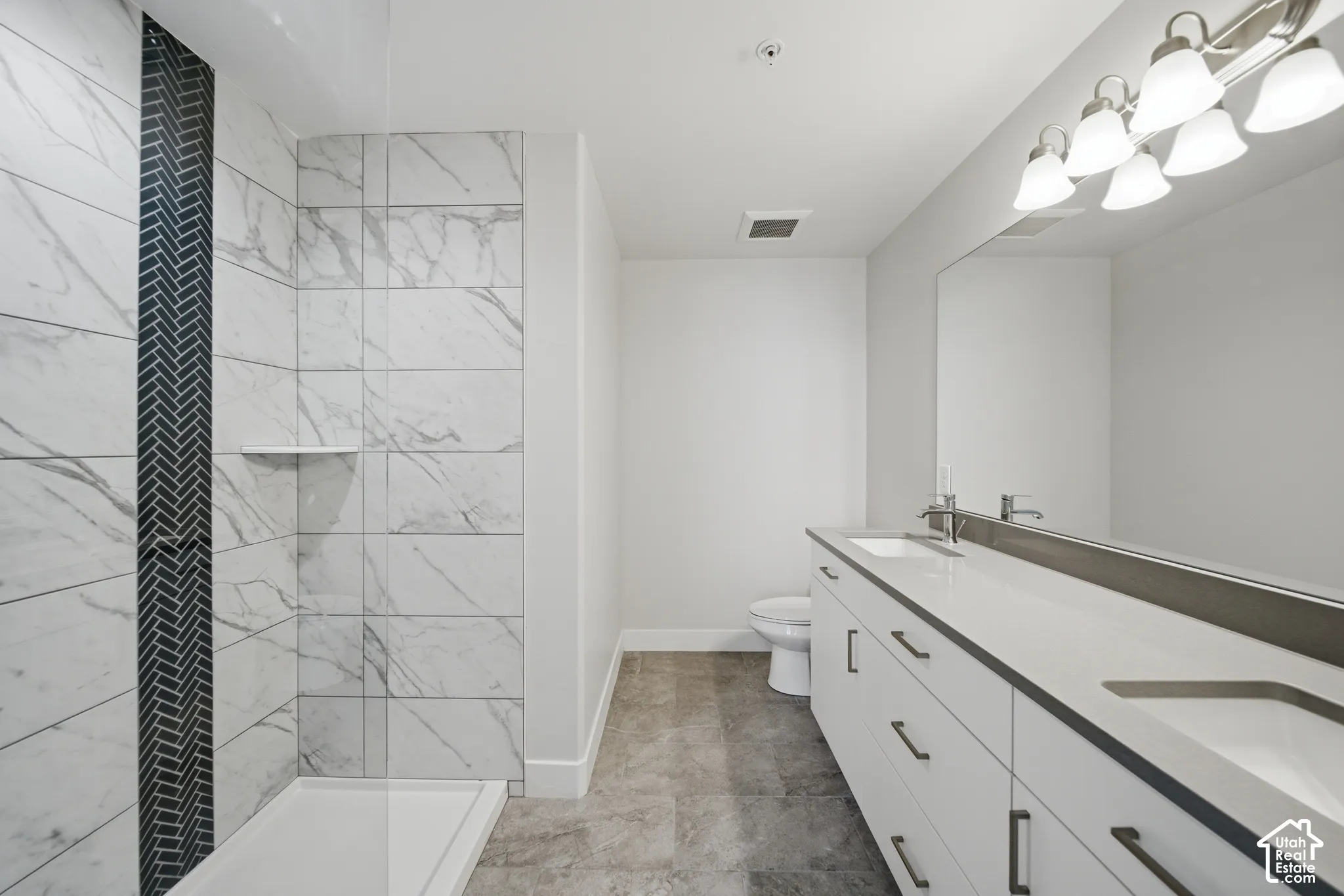 Contemporary bathroom featuring a spacious dual-sink vanity with white cabinetry, a large mirrored surface, and an overhead vanity light fixture
